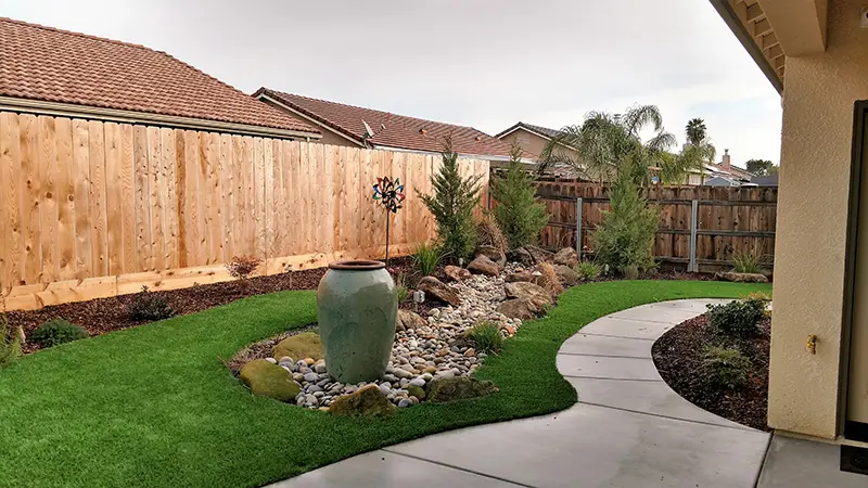 Ways to Make Your Small Backyard Feel Larger - example of small backyard with water feature and hardscaped path